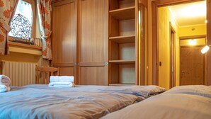 A bedroom with a bed, a wooden wardrobe, and a shelf with towels. - Convenience, comfort and atmosphere at your fingertips (Livigno)