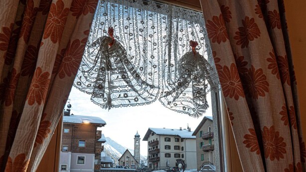 A window view of a snowy town with buildings and a clear sky. - Convenience, comfort and atmosphere at your fingertips (Livigno)
