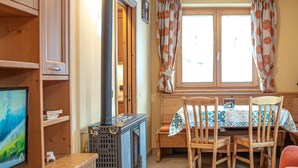 A cozy room with a wooden table, chairs, a television, and a fireplace. - Convenience, comfort and atmosphere at your fingertips (Livigno)