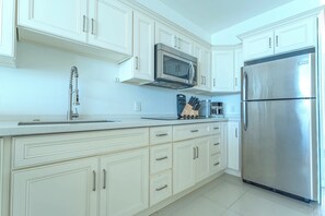 A modern kitchen with white cabinetry, stainless steel appliances, and a tiled backsplash.