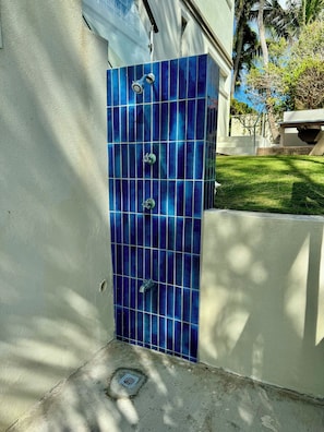 A blue-tiled shower enclosure with a handheld showerhead and a wall-mounted faucet. - Relaxing Beach Front Villa #6 (Grand Cayman)