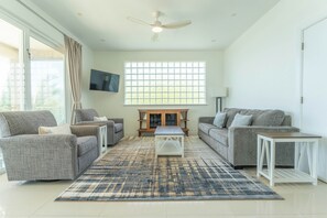 A spacious living room with a large window, two sofas, a coffee table, and a ceiling fan.