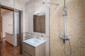 Un baño con ducha de vidrio, lavabo y espejo.