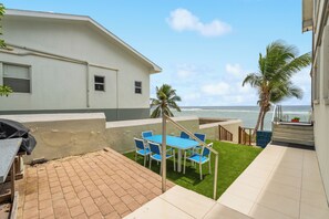 Eine Terrasse mit Tisch und Stühlen, einem Grill und Blick auf das Meer.