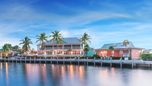 A waterfront hotel with multiple buildings, docked boats, and palm trees.