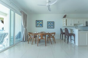 A modern kitchen with white cabinets, a dining area with wooden chairs, and a ceiling fan.