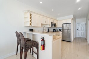 A modern kitchen with white cabinetry, stainless steel appliances, and a built-in island with seating.