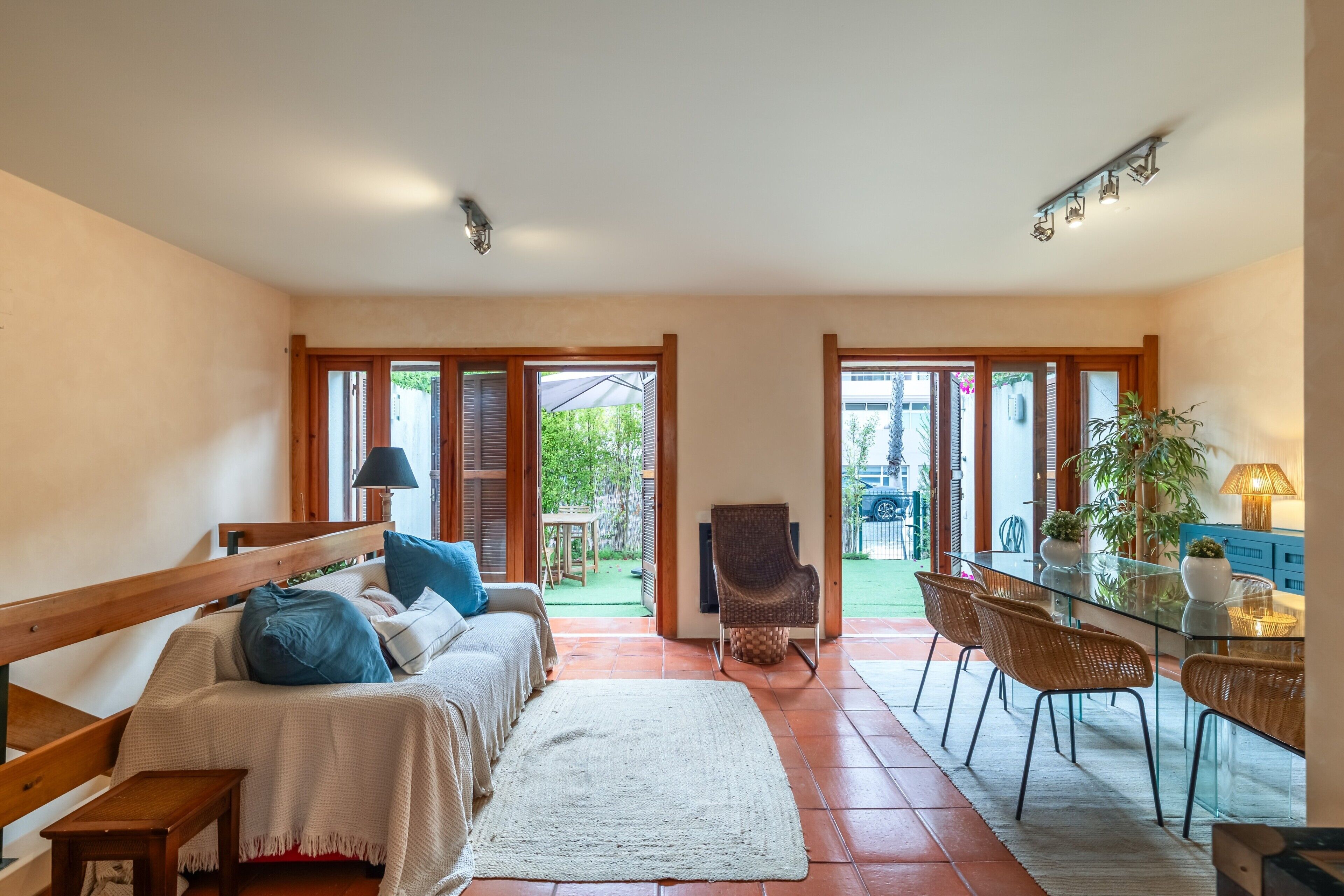 Une pièce spacieuse comprenant un lit, une table à manger et une chaise. On peut apercevoir un jardin à travers la porte ouverte.