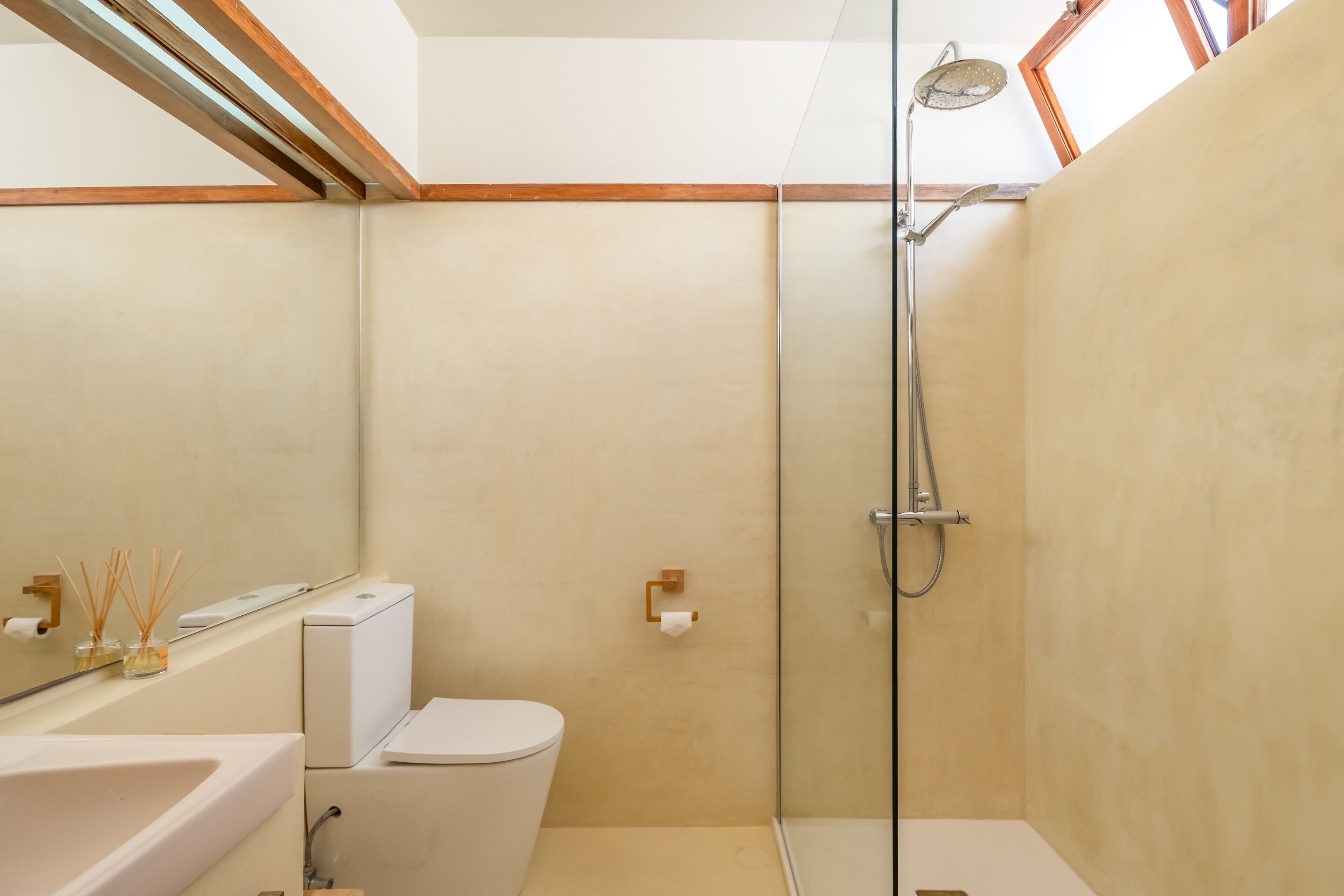 A modern bathroom with a glass-enclosed shower, a toilet, and a sink.