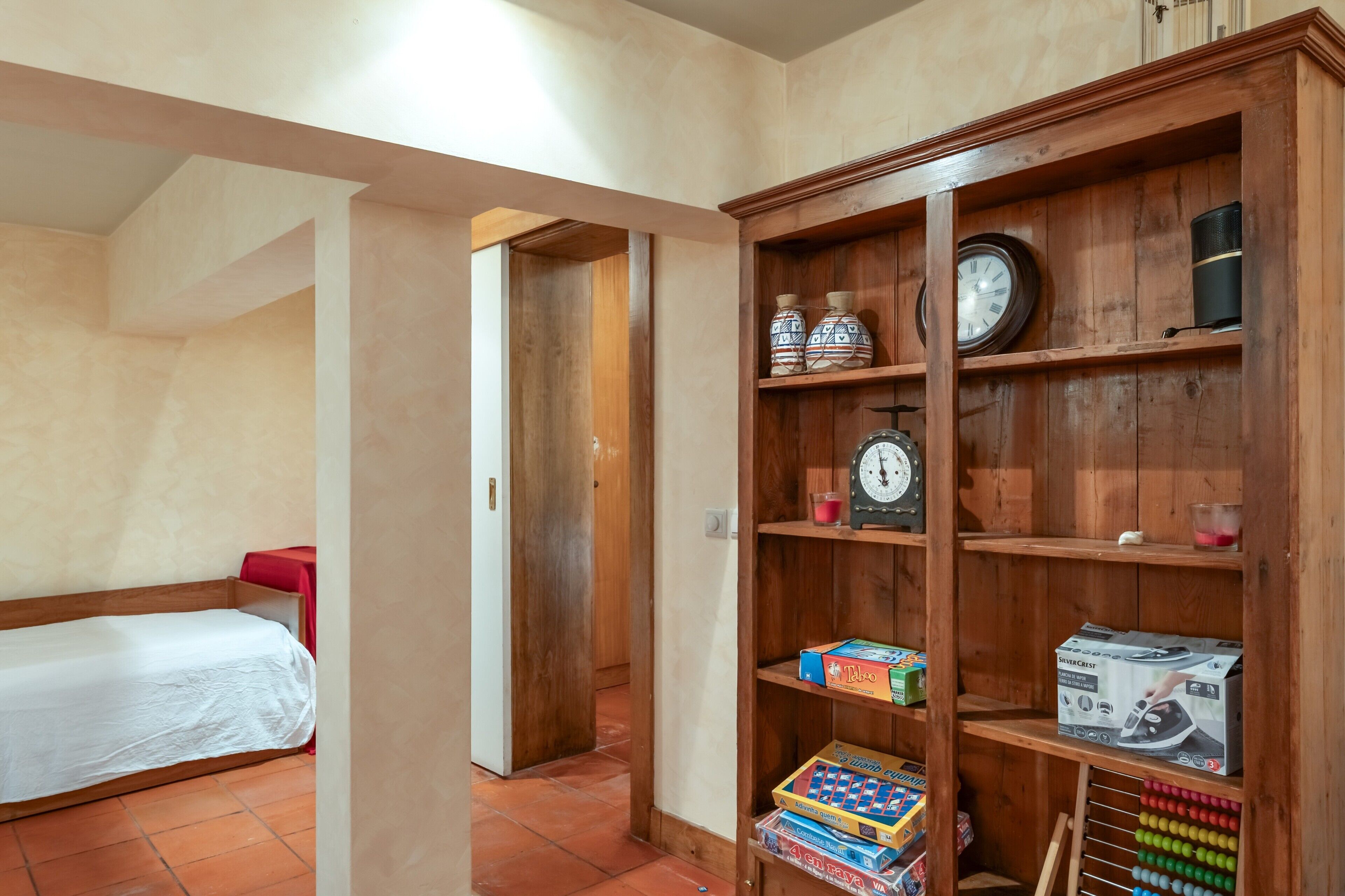 Una habitación con una cama, una estantería de madera y un reloj de pared.