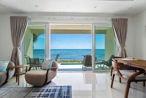 Une pièce avec vue sur l’océan, comprenant une table à manger, des chaises et un canapé.