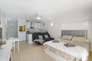 Une chambre moderne comprenant un lit, un canapé, un bureau et un coin cuisine.