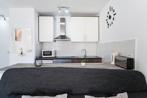 Une cuisine moderne avec des meubles blancs, un four à micro-ondes, un grille-pain et un évier.