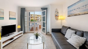 A living room with a TV, sofa, and a glass coffee table. - Vacation Apartment 'Orlando 103' with Shared Pool, Private Terrace and Wi-Fi (Adeje)