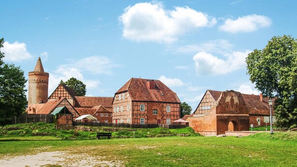 Ein historisches Gebäude mit einem markanten Turm, einem großzügigen Innenhof und traditioneller Architektur.