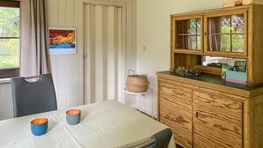 Ein Essbereich mit Tisch, Stühlen und einem Holzschrank mit Glastüren.