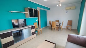 A modern living room with a TV, sofa, and dining area.
