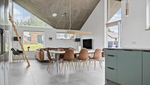 Eine moderne Küche mit Essbereich, ausgestattet mit einem großen Fenster, einem eingebauten Backofen und einer Holzbalkendecke.
