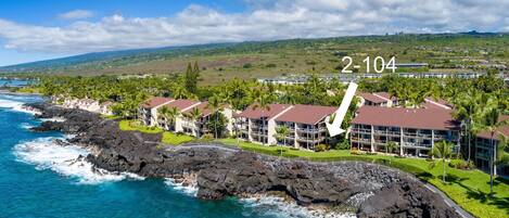 A coastal hotel with a rocky shoreline, multiple buildings, and a clear view of the ocean.