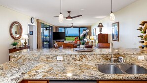 A kitchen with granite countertops, a double sink, and a view to the outdoors. - Spectacular Ocean Front, Garden Level, Corner Unit, Stunning Views for 4 in Kona (Kailua Kona)