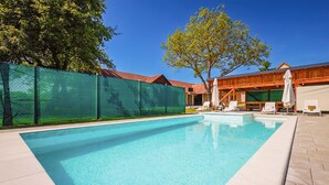 A swimming pool with clear blue water, surrounded by a green fence, and white lounge chairs. - Awesome home in Ivanska (Ivanska)