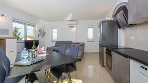 Una cocina moderna con comedor, sofás grises y un televisor grande.
