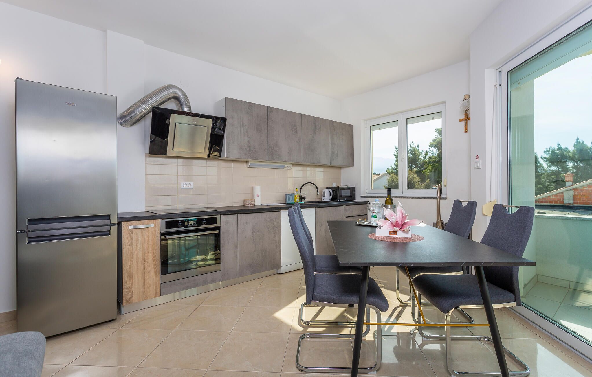 Een moderne keuken met een eethoek, voorzien van roestvrijstalen apparatuur, een groot raam en uitzicht op de omgeving.