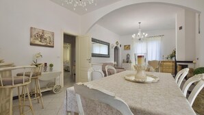 A dining area with a long table, chairs, a chandelier, and a painting on the wall. - Cozy apartment in Capezzano Pianore (Capezzano Pianore)
