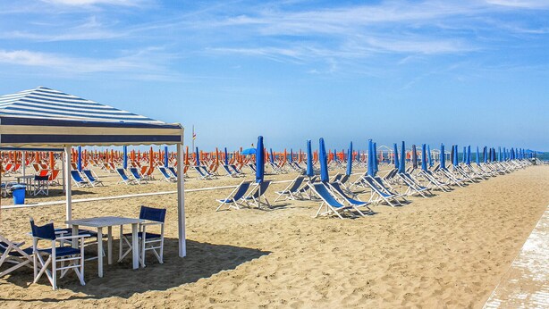 A beach with rows of sun loungers and umbrellas, a covered seating area, and a clear sky. - Cozy apartment in Capezzano Pianore (Capezzano Pianore)
