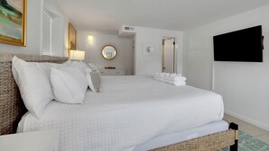 Een netjes ingerichte slaapkamer met een groot bed, een nachtkastje, een spiegel en een flatscreen televisie aan de muur.