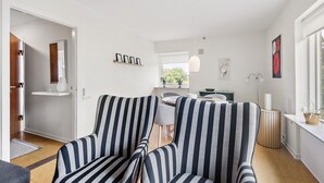 A modern living room with striped armchairs, a dining area with a round table, and a view of the outdoors through a window. - Cozy home in Nørre Nebel with WiFi (Nørre Nebel)