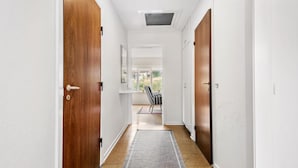 A hallway with wooden doors, a ceiling vent, a window, and a striped chair. - Cozy home in Nørre Nebel with WiFi (Nørre Nebel)