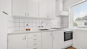 A modern kitchen with white cabinets, a stainless steel sink, and a built-in oven. - Cozy home in Nørre Nebel with WiFi (Nørre Nebel)