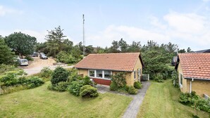 A residential area with a house featuring a red-tiled roof, a paved driveway, and a well-maintained lawn. - Cozy home in Nørre Nebel with WiFi (Nørre Nebel)
