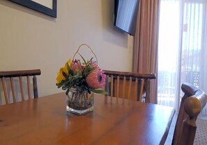 Une table à manger en bois sur laquelle est posé un vase en verre transparent contenant des fleurs.