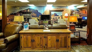 A lobby with a large sofa, a wooden cabinet, and a TV.