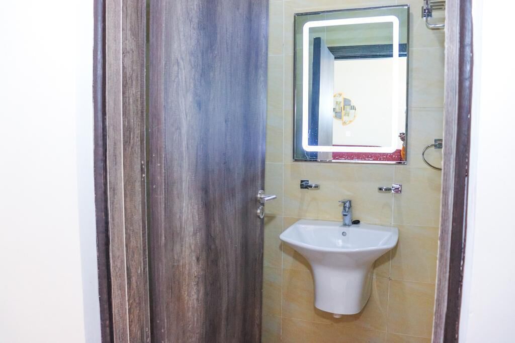 A bathroom with a wooden door, a white sink, and a mirror above it.