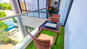 Un balcon avec une table et des chaises, une rambarde en verre et une vue sur l’extérieur.