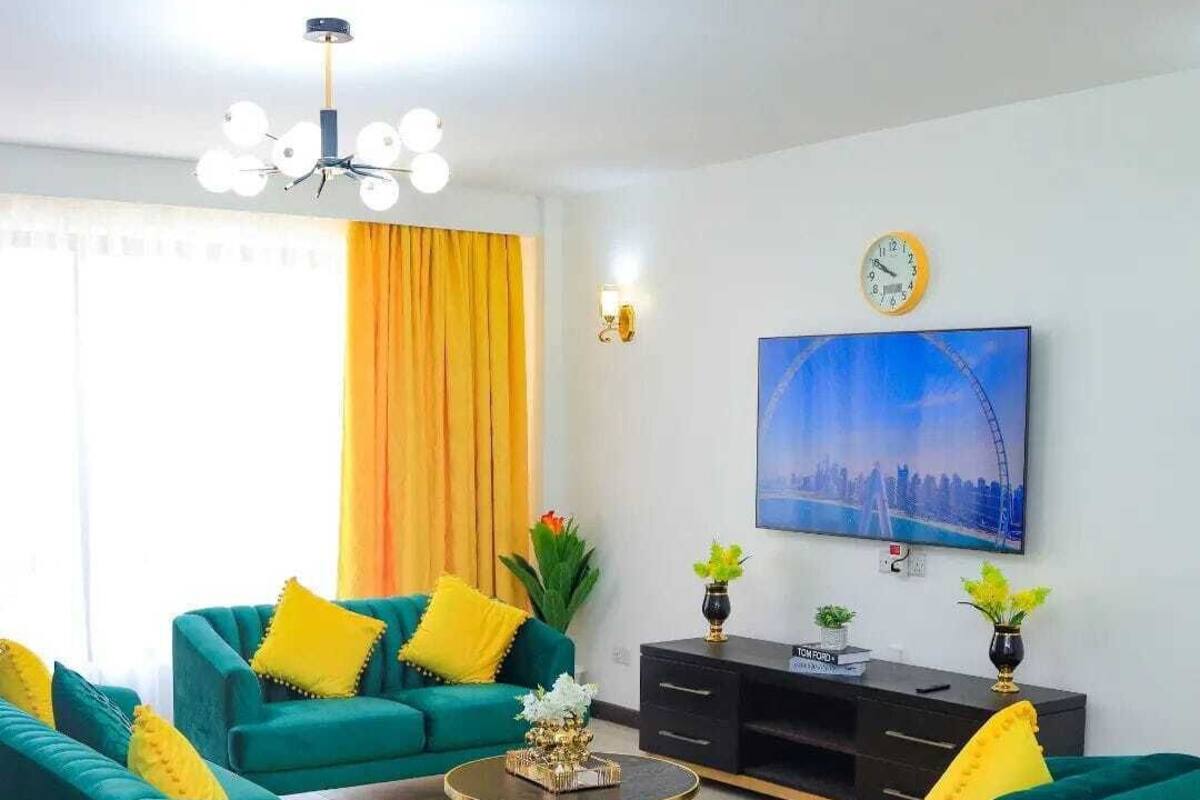 Una sala de estar moderna con sofás color turquesa, una mesa de centro y un televisor en la pared.