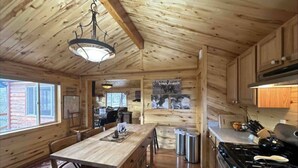 Ein rustikales Holzhaus-Interieur mit Essbereich, Küche und einem großen Fenster.