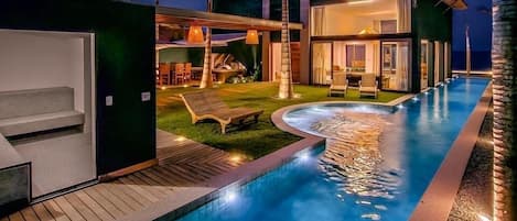 Un área de piscina moderna con vista despejada, sillas de descanso y un espacio exterior bien iluminado.
