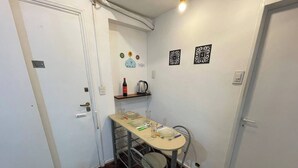 A small dining area with a table, chairs, and a shelf with a bottle and a kettle. - Charming 2-room Temporary Stay in the Heart of San Telmo (Buenos Aires)