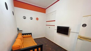 A small room with a bed, a television, a wardrobe, and a door. - Charming 2-room Temporary Stay in the Heart of San Telmo (Buenos Aires)