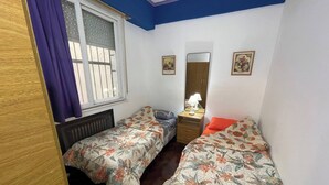 A bedroom with two single beds, a window with blinds, a dresser, a mirror, and two wall-mounted pictures. - Charming 2-room Temporary Stay in the Heart of San Telmo (Buenos Aires)
