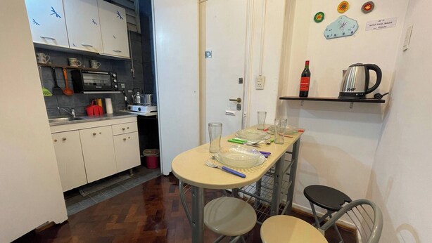 A compact kitchen with white cabinets, a microwave, and a kettle on a shelf. - Charming 2-room Temporary Stay in the Heart of San Telmo (Buenos Aires)