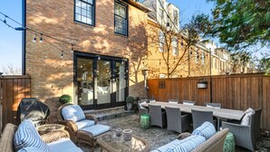A patio with wicker furniture, a table, and a brick wall.