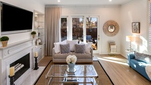 A living room with a fireplace, a sofa, a coffee table, and a TV mounted on the wall.