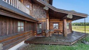 Una baita di legno con veranda, un tavolo e una panca.