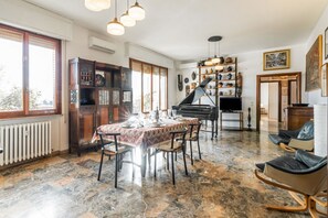 Uma área de refeições com piso de mármore, um piano e uma mesa de jantar posta para quatro pessoas.