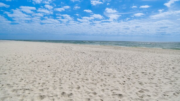 A wide sandy beach with footprints leading to the water. - Family-Friendly Pensacola Home < 1 Mi to Beach! (Pensacola)